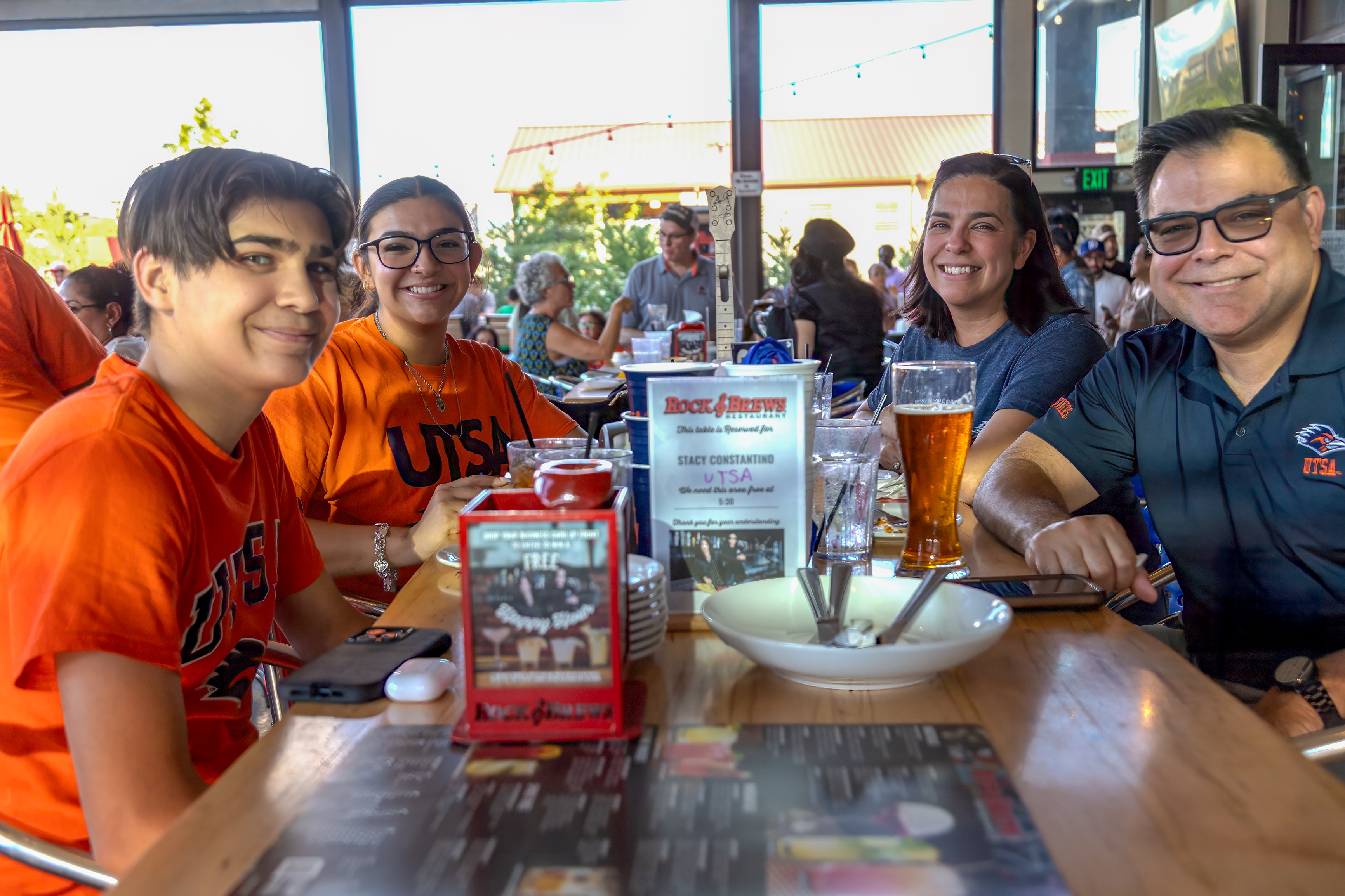 A man and woman sit at a table with their students smiling at a table in a resturant.