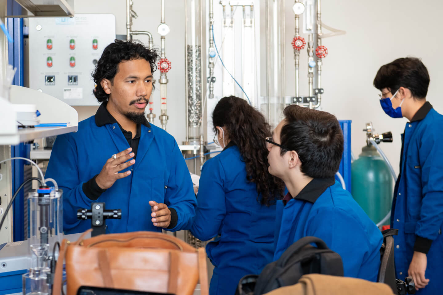 Students and professor inside a lab wearing blue coats
