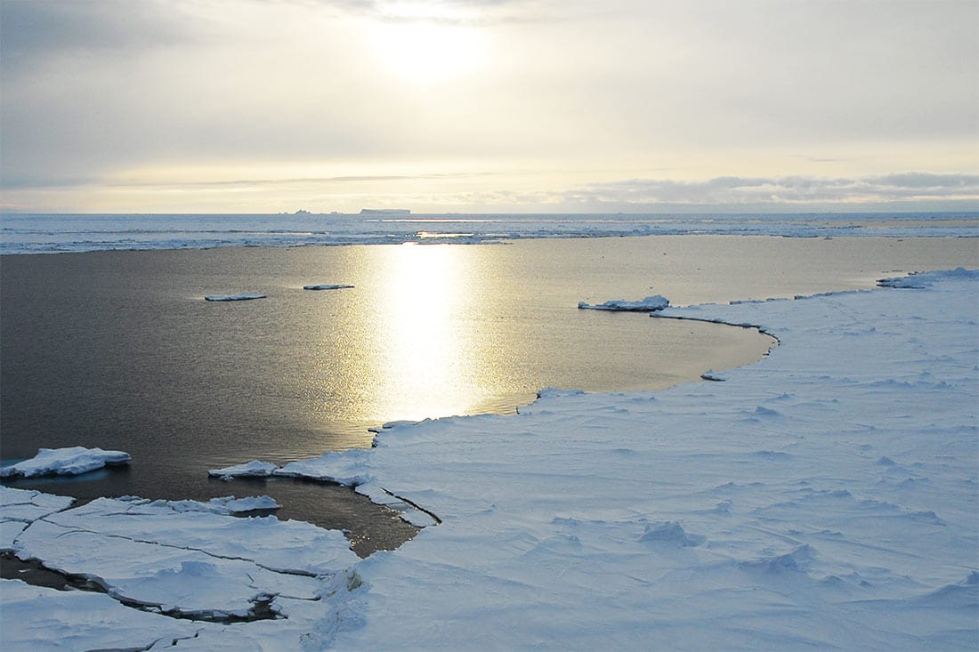 The sun sets over Antarctic ice floes.