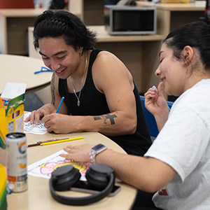 Two students sitting at a table coloring.