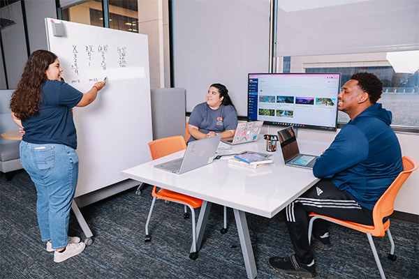 Student explaining to two other students that are sitting
