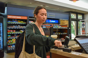 A student swiping their meal card at a register.